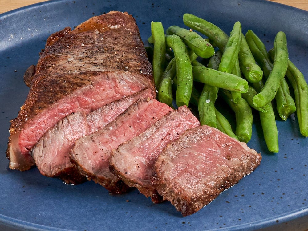 Aspen Ridge steak with green beans on a blue plate